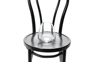 A 17cm glass mushroom vase sitting on a black bentwood chair with a white background. Close up image of the small mushroom vase.