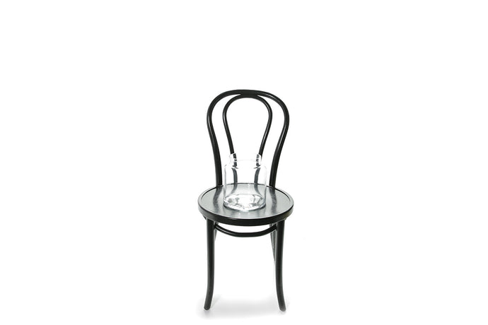 20cm lipped cylinder vase sitting on a black bentwood chair with a white background.