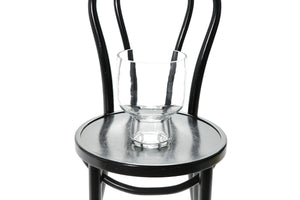 Large 24cm compote glass vase sitting on a black bentwood chair with a white background. Close up image of vase.