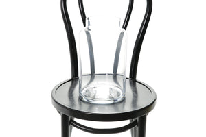 30cm lipped cylinder vase sitting on a black bentwood chair with a white background. Close up image of vase.