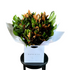 Close up image of A large bouquet of magnolia foliage and monsteria leaves, beautifully gift wrapped in white signature wrapping and placed into kate hill flower bag. Bouquet sitting on black bentwood chair with white wall background.