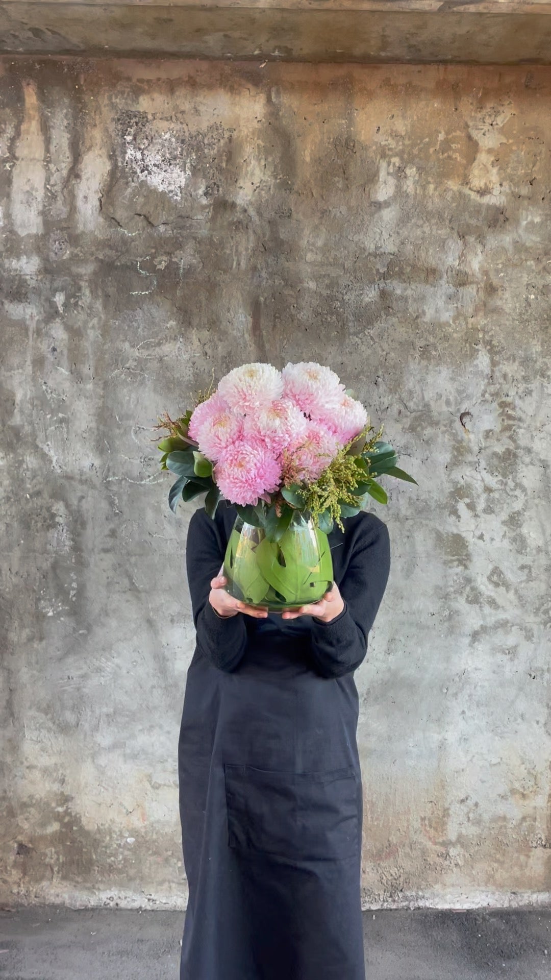 Video of florist holding the tapered vase displaying blush pink disbuds and green foliage.