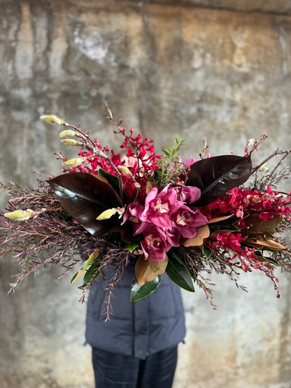 Florist holding the GARNET rich red tablescape against a concrete wall. 