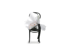 Wide image of Annette blush orchid stem.A beautiful single stem of blush phalaenopsis orchid, stylishly wrapped in our signature white wrapping. Annette bouquet laying on a black bentwood chair with a white background.