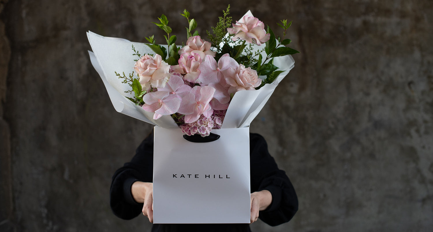 Melbourne florist Kate Hill with flower delivery for Armadale in white bag with pink hues. 