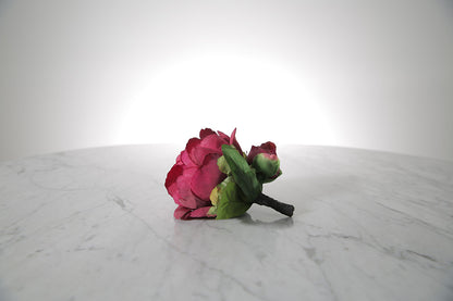Kate Hill Flowers – artificial burgundy peony rose buttonhole flower with green leaf backing and pearl pin on marble table setting. 