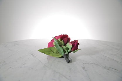 Kate Hill Flowers – artificial burgundy peony rose buttonhole flower with green leaf backing and pearl pin on marble table setting. 