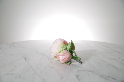 Kate Hill Flowers – artificial pale pink peony rose buttonhole flowers with green leaf backing and pearl pin set on a marble table.
