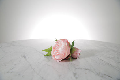 Kate Hill Flowers – artificial pale pink peony rose buttonhole flowers with green leaf backing and pearl pin set on a marble table.