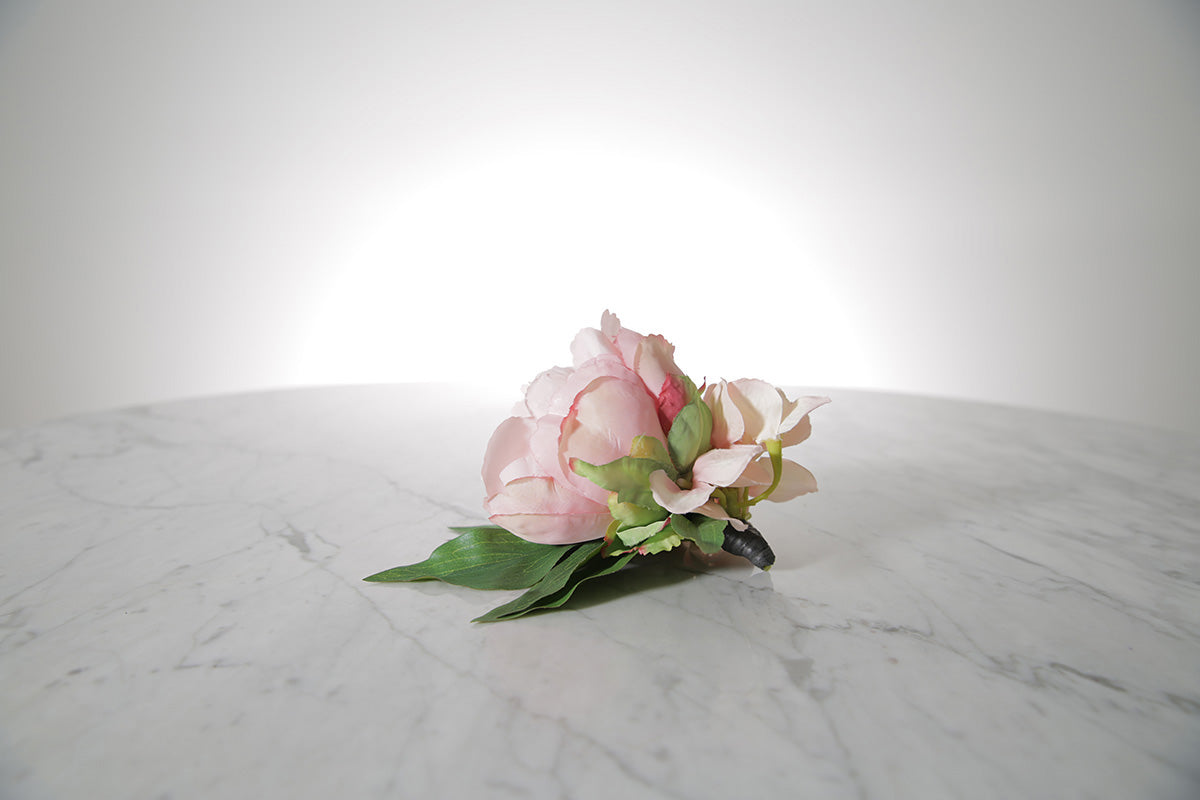 Kate Hill Flowers – pink spray rose buttonhole flowers with black-taped stem and pearl pin on marble table setting.