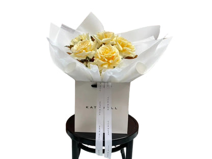 Close up image of our August Birthday Bouquet in lemon and cream tones, sitting on a black bentwood chair.