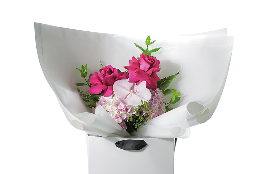 Kate Hill Flowers – small blush pink graduation bouquet with roses, orchid and foliage, hand-tied on a white background.