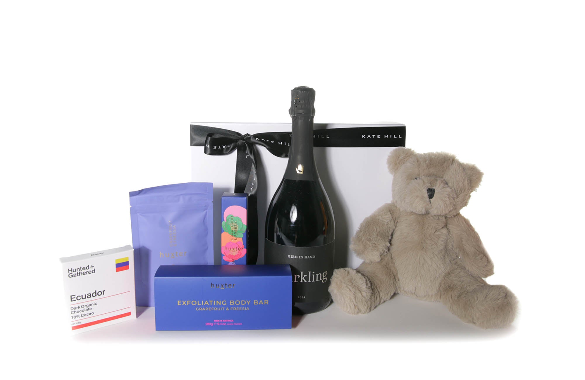 Gift box hamper featuring a chocolate bar, body care pack, Australian sparkling wine and a teddy bear.