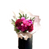 A large bouquet of flowers in hot pink, magenta and burgundy colours, detailed with a hint of Christmas spruce foliage. Bouquet is wrapped beautifully in white signature wrapping and florist is standing against a white wall. 