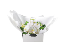 White and green with a pop of yellow lemon medium sized bouquet, beautifully wrapped in white signature presentation. Bouquet is placed into Kate Hill flower bag to ensure the bouquet remains fresh in water. Bouquet bag is sitting on a black bentwood chair with a white background. Close up image of the bouquet.