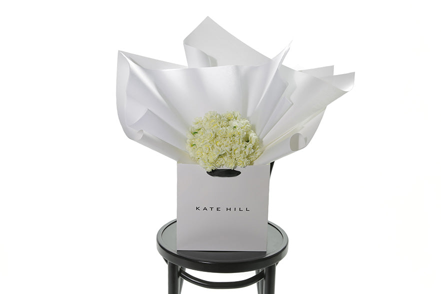 Petite posy of fragrant Erlicheer beautifully wrapped in signature white wrapping. The CLAIRE Flower Bouquet is a short, petite posy bunch featuring gift wrapped Erlicheer which make a beautiful gesture gift for any occasion. Or a beautiful cut bunch for Home.  Classed as a small in size, the CLAIRE is a hand tied collection of 3 bunches of Erlicheer which are beautifully gift wrapped in our signature wrapping. CLAIRE Erlicheer flower bunch sitting on a black bentwood chair.