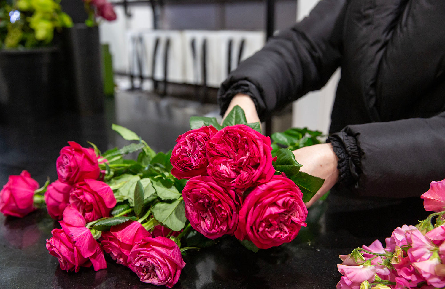 Florist in Caulfield arranging pink flowers on a black work bench