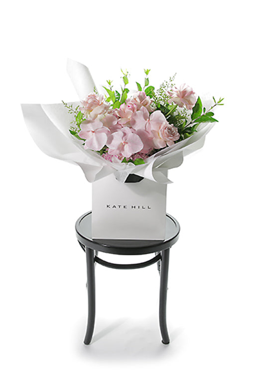 Pink bouquet of flowers on bentwood with white backdrop