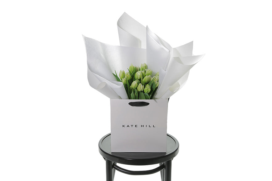 Kate Hill flower bag sitting on a black bentwood chair, displaying fresh premium white double tulip bouquet. Bouquet of 20 stems of white double tulips in image.