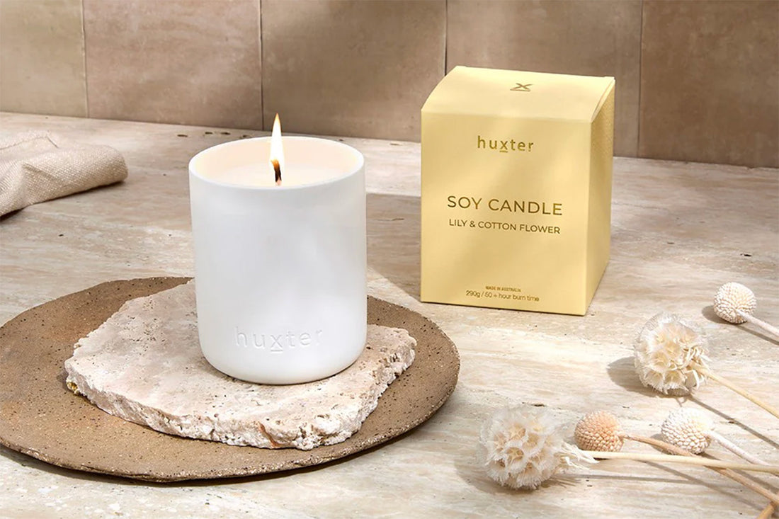 White candle on a stone coaster with a gold &