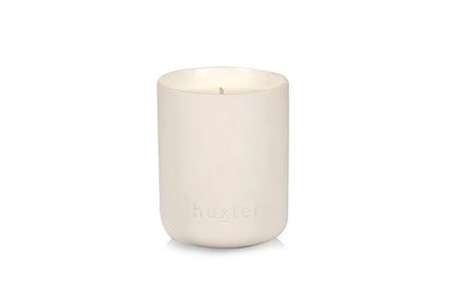 White Huxster candle in a ceramic holder on a white background