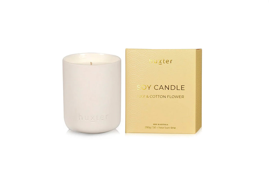 White Huxster candle with a gold box labeled &
