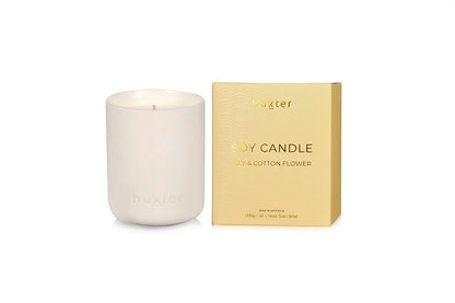 White Huxster candle with a gold box labeled &