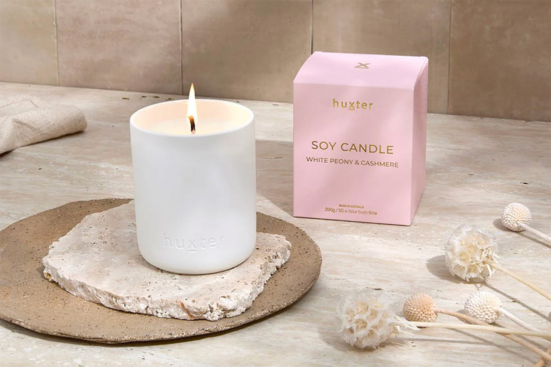 White candle on a stone coaster with a pink &