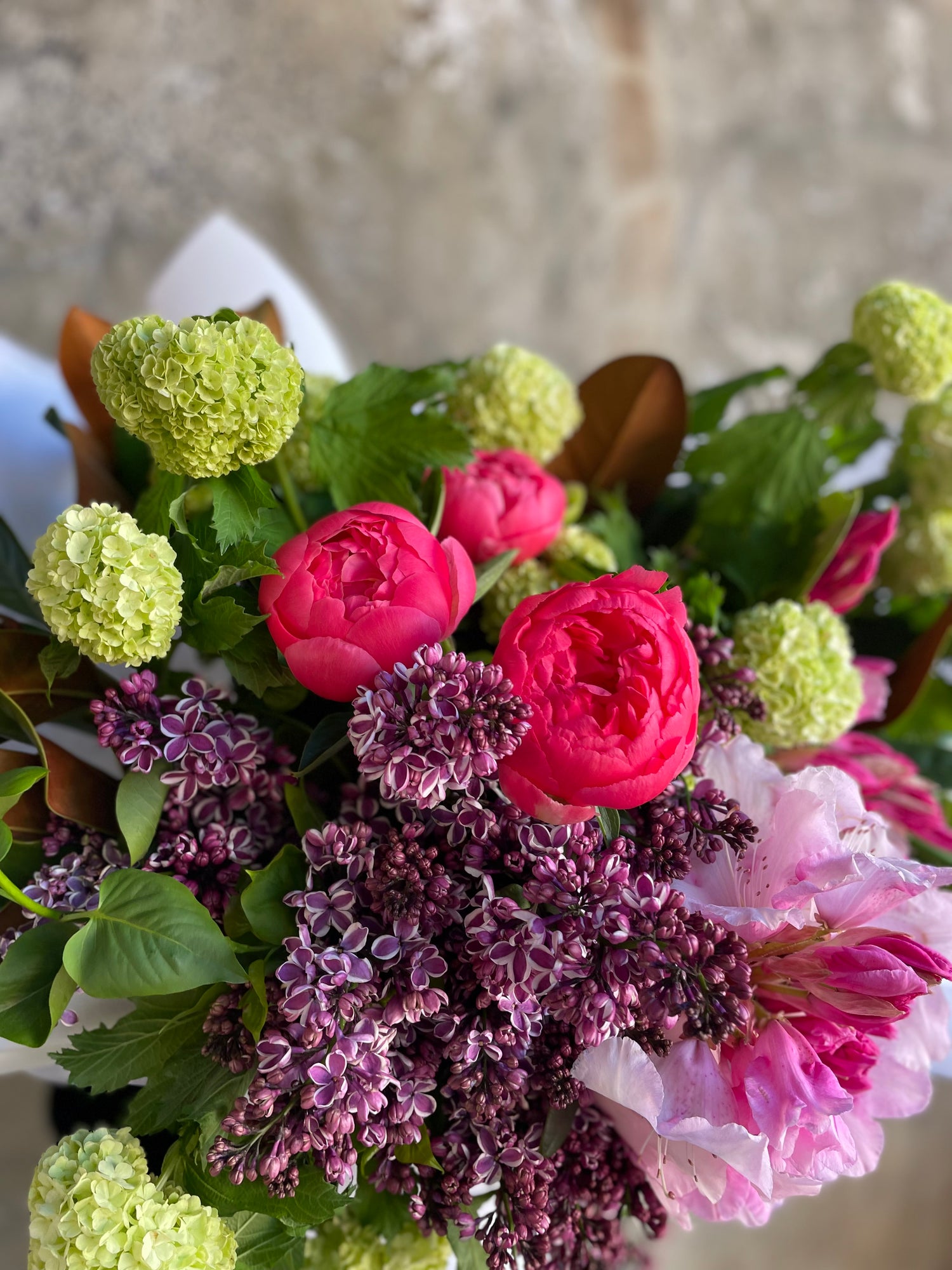 Close up image of spring mixed bouquet featuring snowball, peonies, rhododendron, lilac. mixed jewel bouquet. 