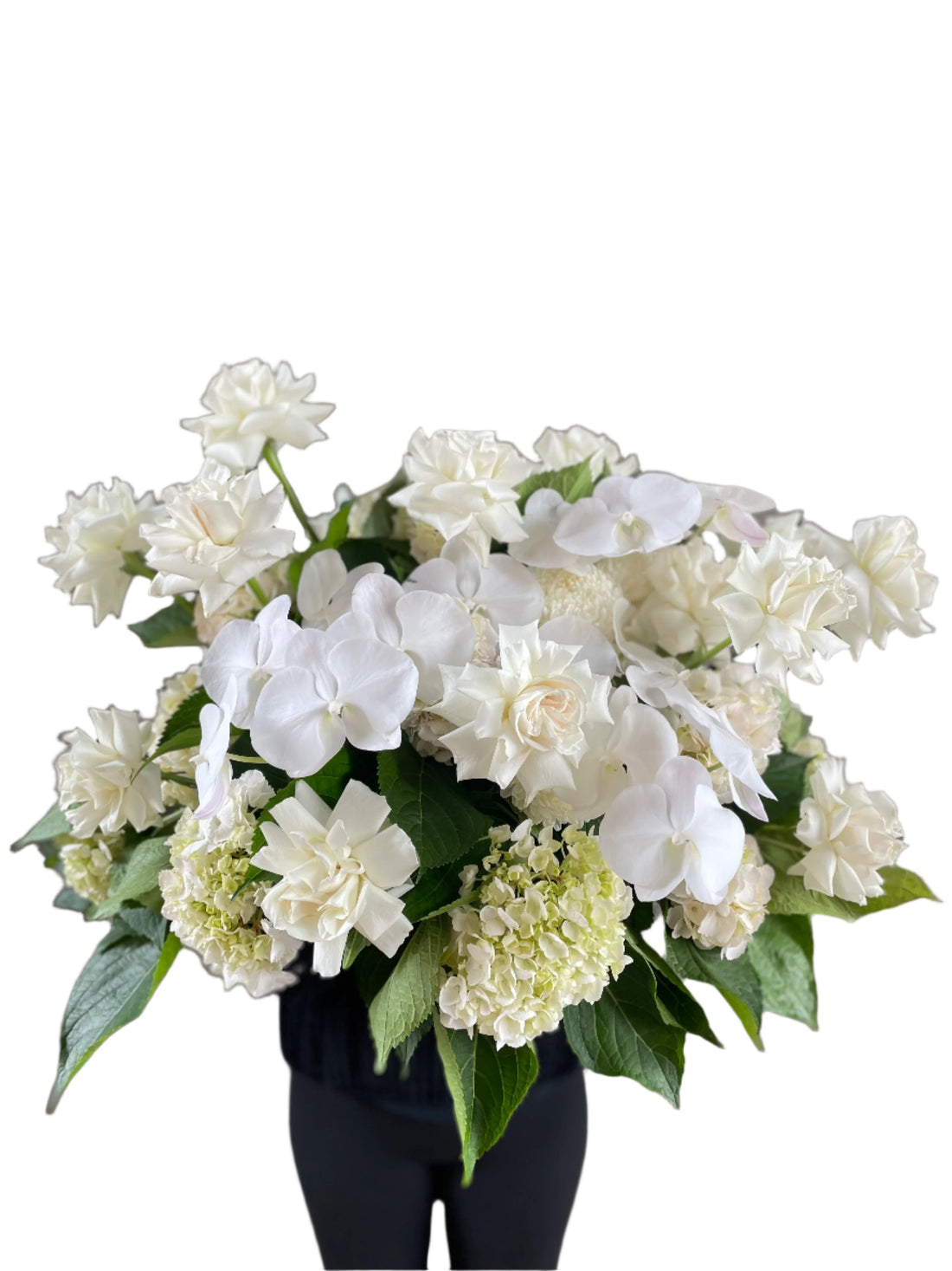 Large white and green casket tribute design, being held by a florist wearing black and standing in front of a white wall.