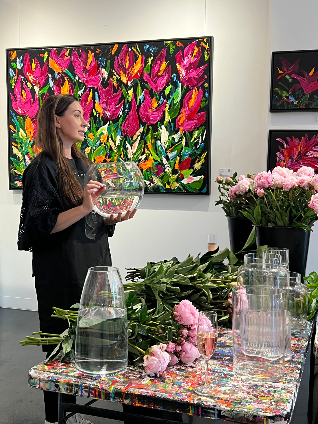 Kate Hill holding a vase as she hosts a Peony Rose flower workshop, surrounded by Peony Roses, vases and Plume art work.