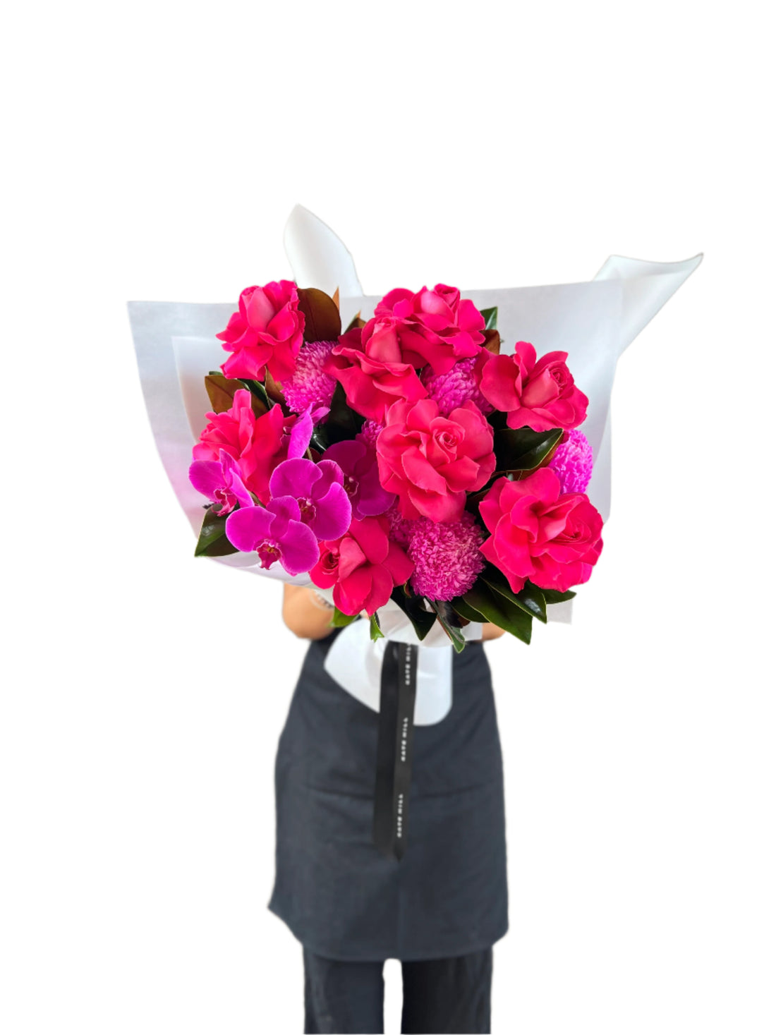 A florist wearing black, holding a large hot pink and magenta bouquet against a white wall.