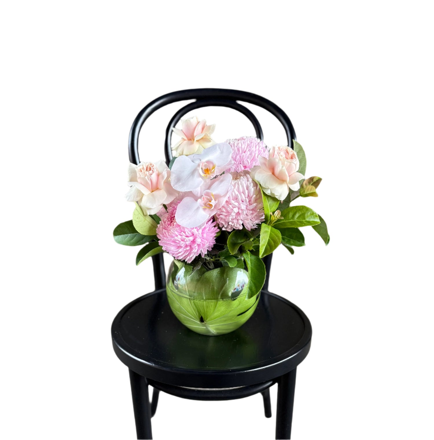 A soft pastel pink ball vase design sitting on a black bentwood chair.