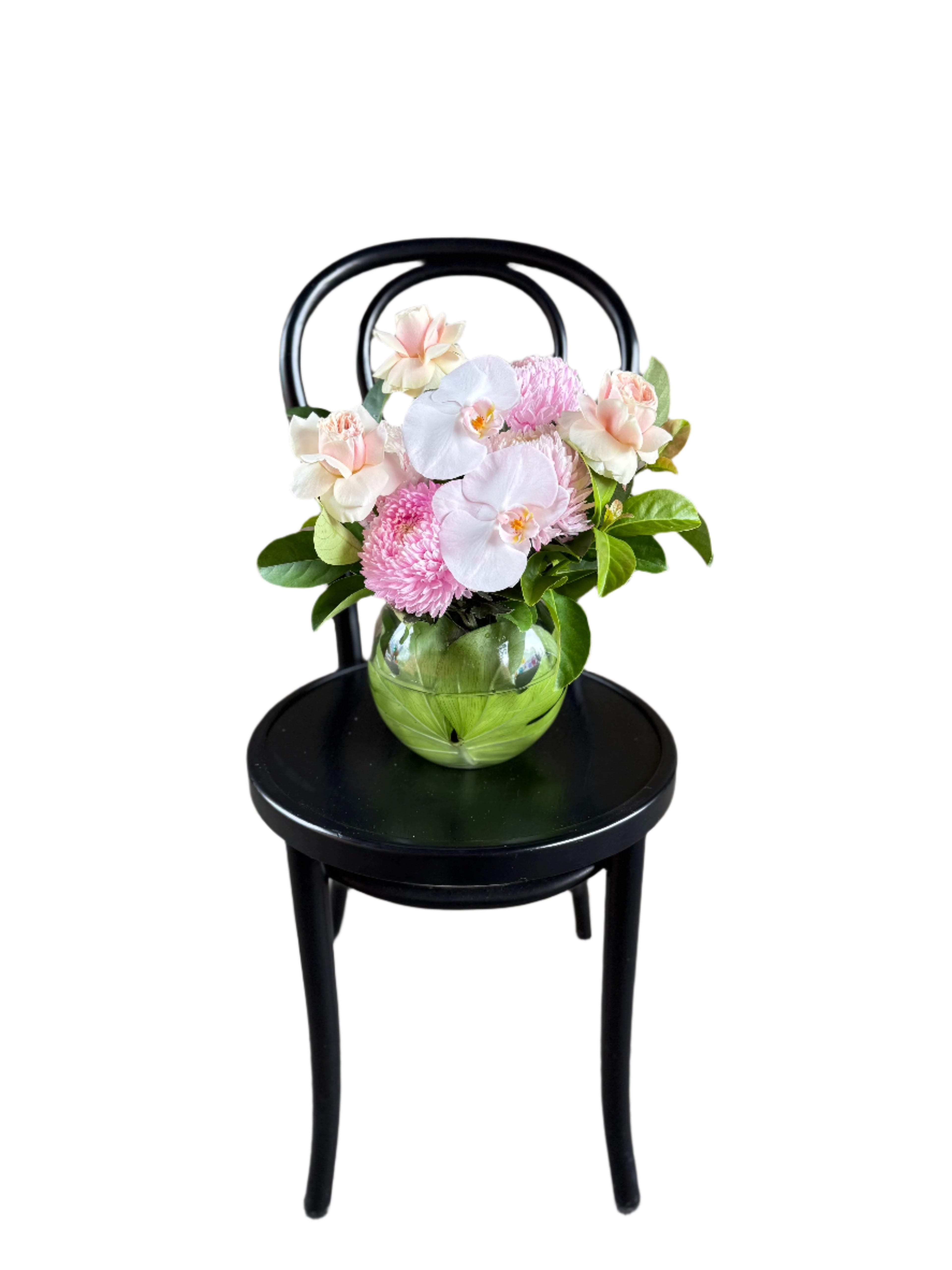 A wide image of soft pastel pink ball vase design sitting on a black bentwood chair.