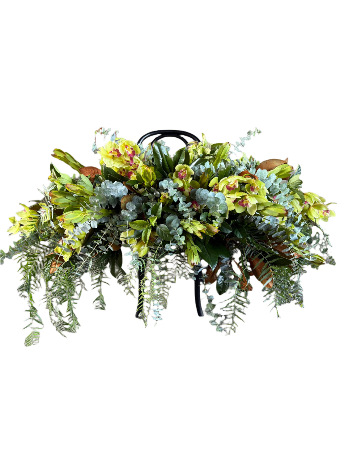 A green and native funeral casket spray displayed on a black bentwood chair white background.