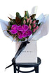Bouquet of bright pink flowers on a black bentwood chair against a white wall.