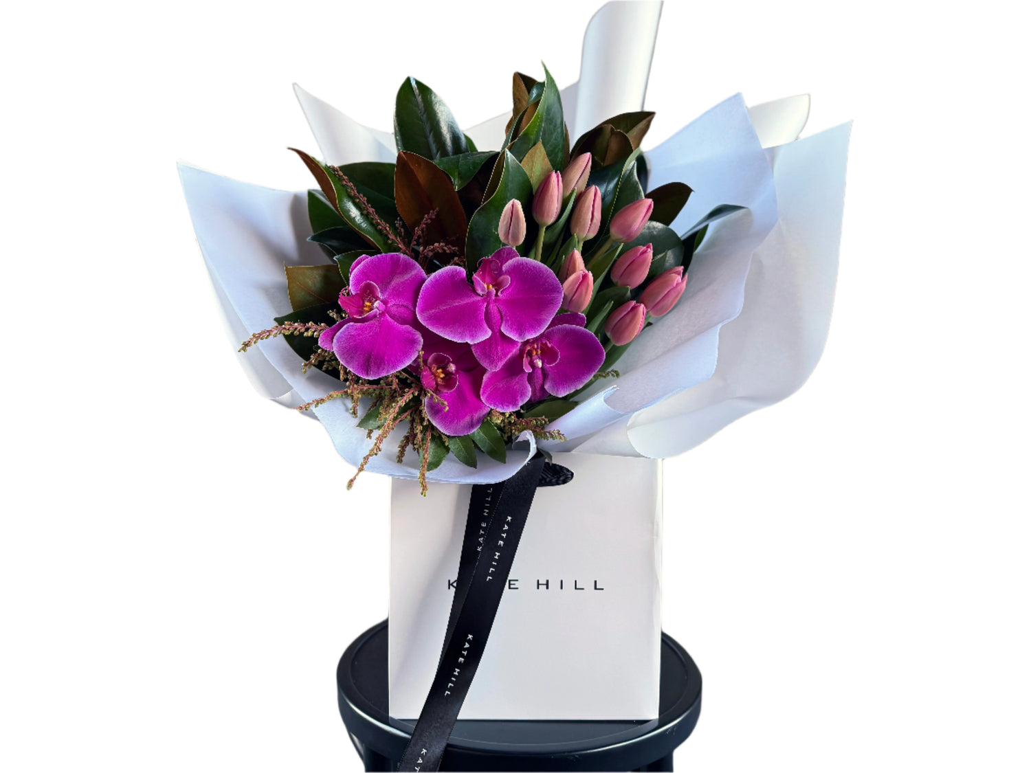 Bouquet of bright pink flowers on a black bentwood chair against a white wall.