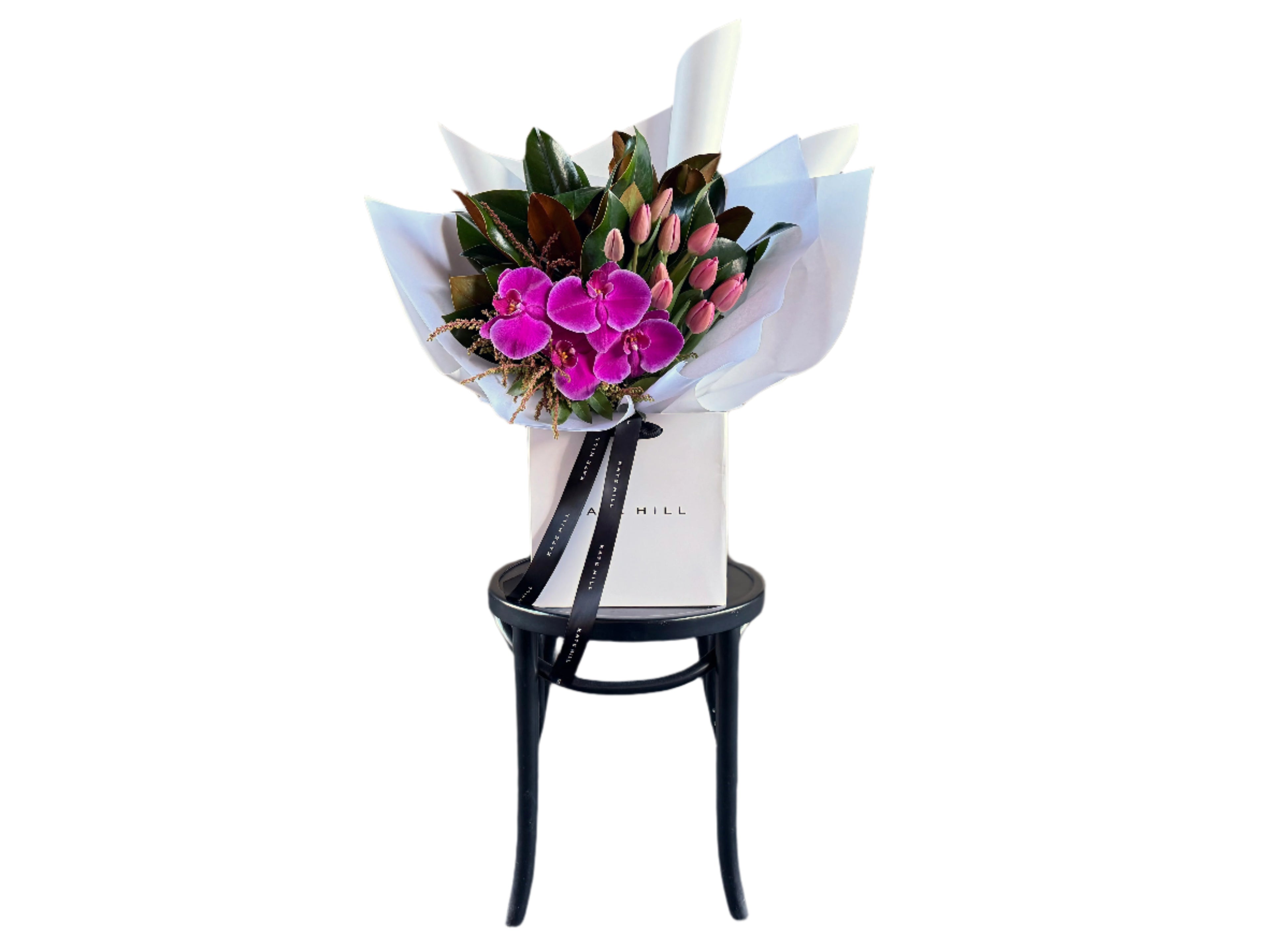 Bouquet of bright pink flowers on a black bentwood chair against a white wall.
