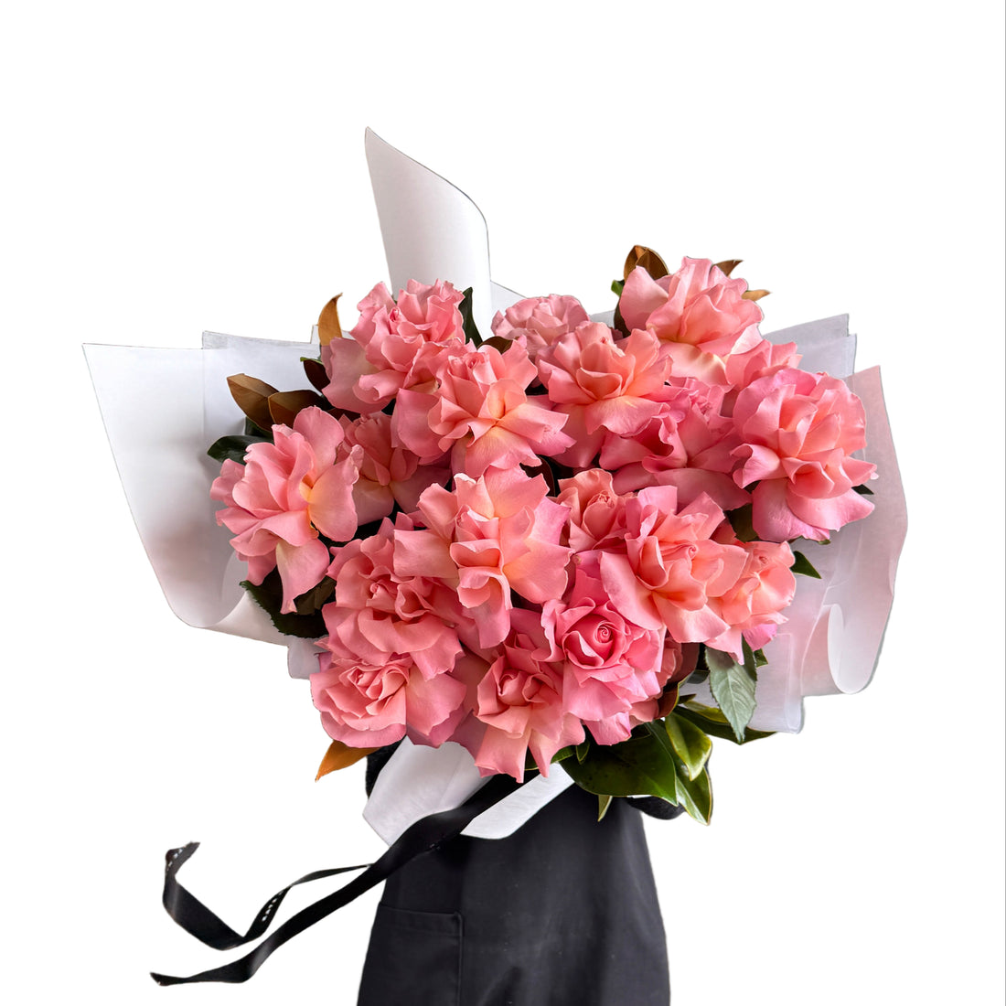 Florist holding a bouquet of watermelon pink rose flowers wrapped in white paper against a white wall background. 