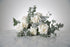 Bridal bouquet of white roses and eucalyptus on a marble surface with a light grey background