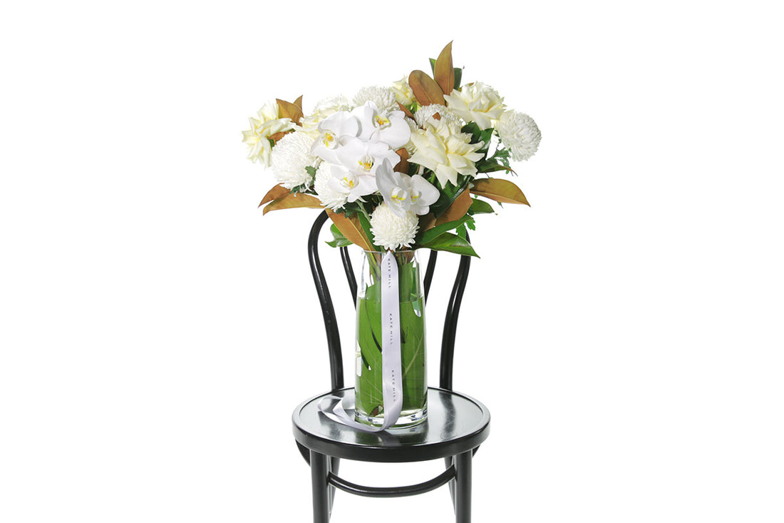 Kate Hill Flowers – large tapered vase with white and lemon roses, chrysanthemums, orchids and monstera lining.