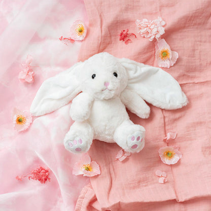 White plush bunny toy on a pink fabric background with flowers