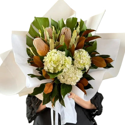 A florist wearing black holding a March birthday bouquet against a white wall.