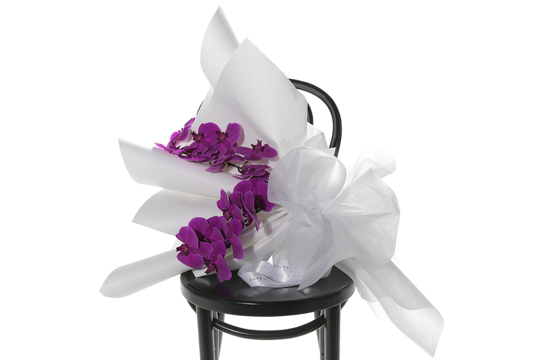 Kate Hill Flowers – gift-wrapped magenta Phalaenopsis orchid bouquet with two water-vialled stems.