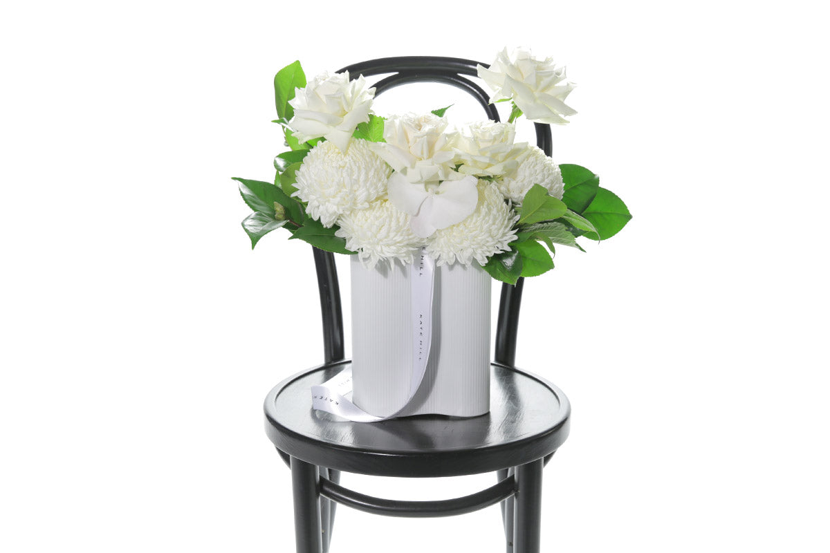 Kate Hill Flowers – medium white sympathy vase with roses, chrysanthemums, orchids and greenery in a wave-ceramic vessel.