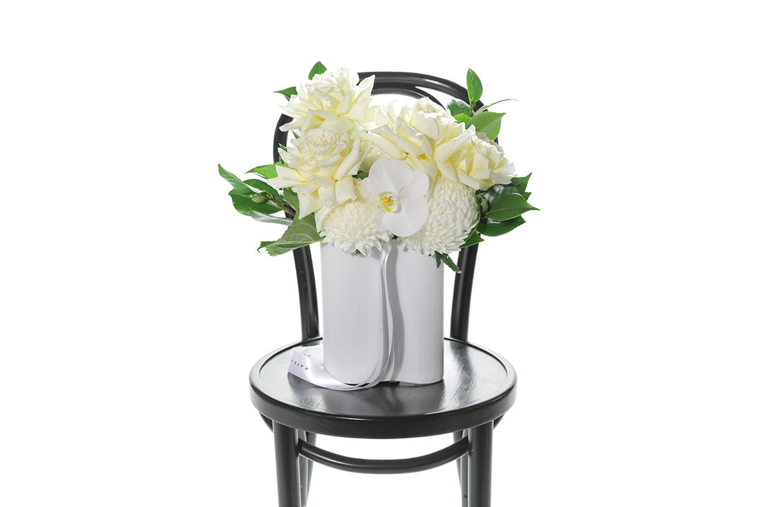 Kate Hill Flowers – white and lemon congratulations vase with roses, chrysanthemums, orchids and foliage in a white wave ceramic.