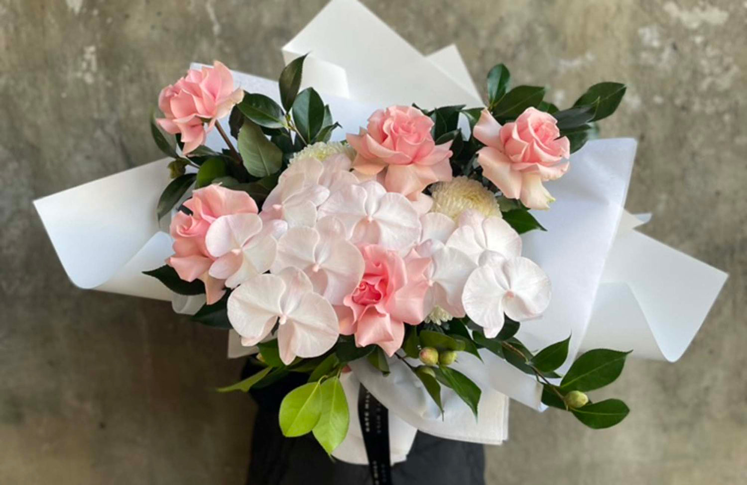 Bouquet of pink and white flowers with green leaves for delivery to Middle Park with a textured concrete background.
