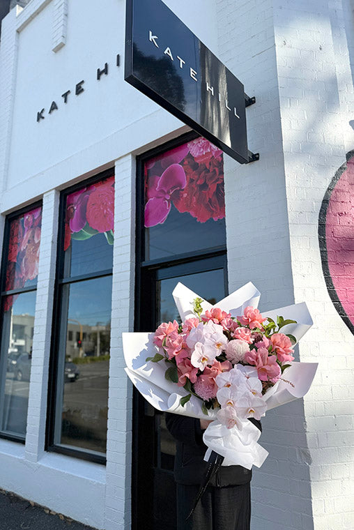 Florist holding bouquet ready for delivery to Middle Park in front of Kate Hill Flowers.