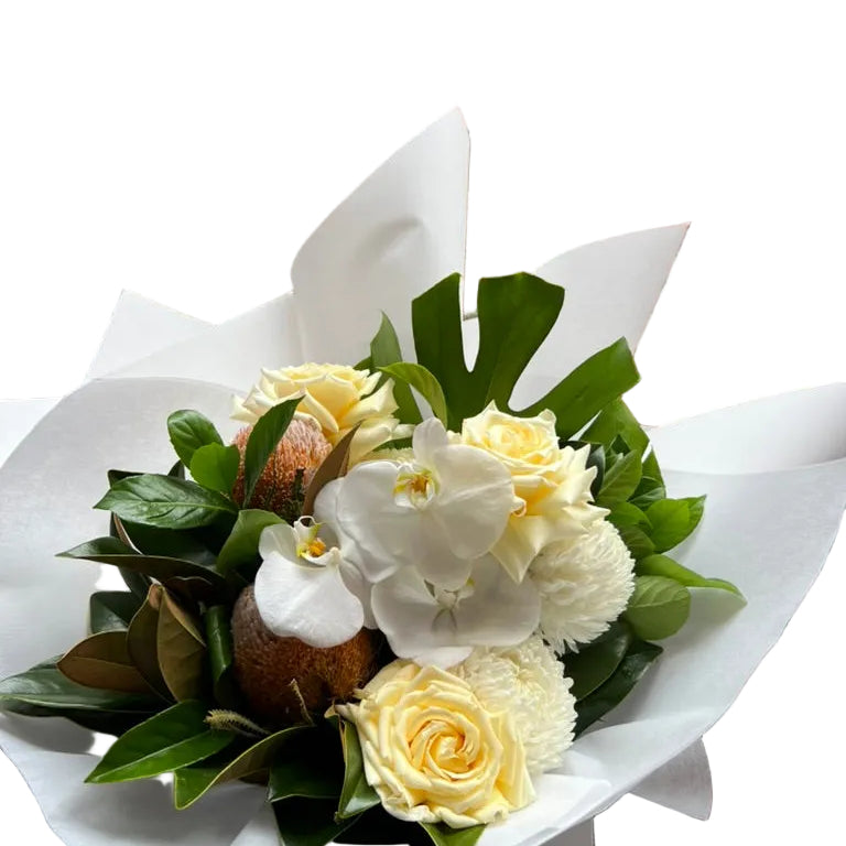 Close up of our October Birthday Bouquet featuring lemon roses, banksias, white disbuds, white orchid and seasonal foliage. Presented beautifully in our signature white wrapping.