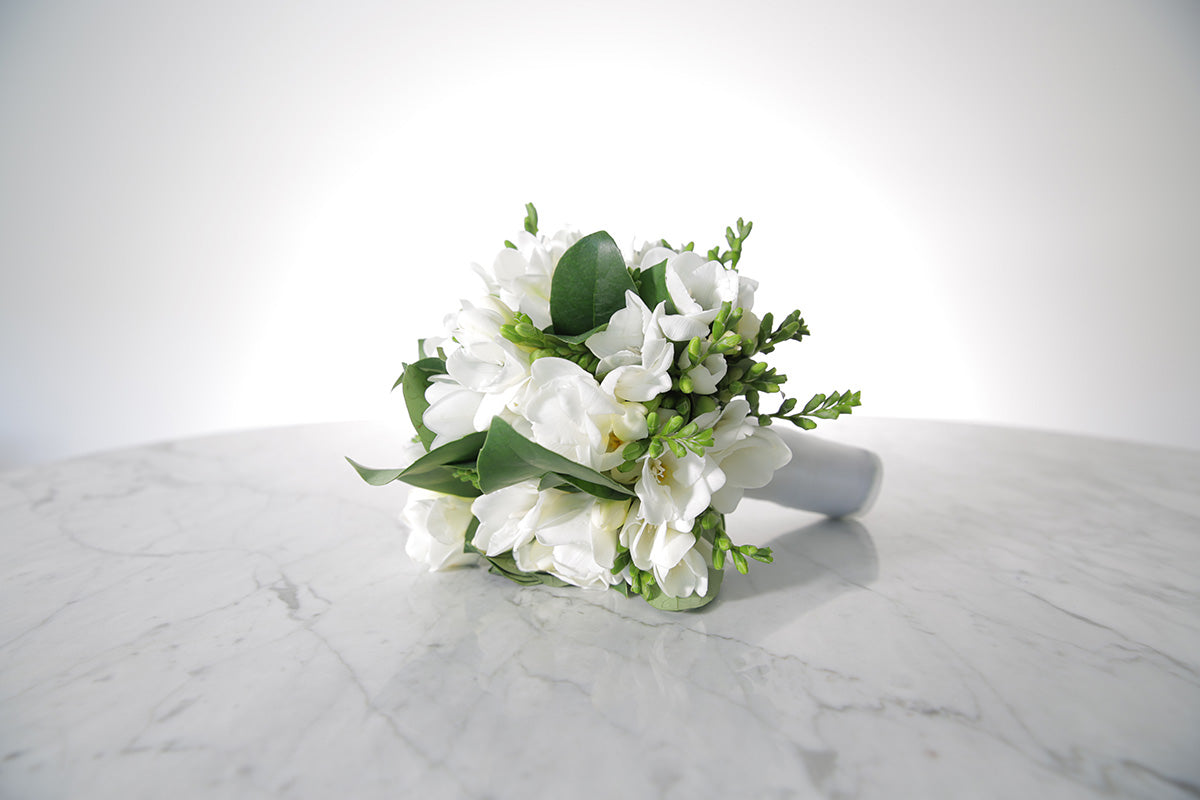 White wedding flower bouquet on a marble surface with a white background